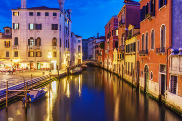 Venice cityscape at night with bright lights, Grand canal and floating boats.