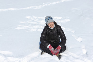 Fototapeta na wymiar Cheerful smiling woman squating cross-legged on snow