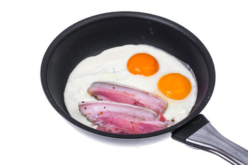 Fried eggs and bacon in frying pan on white background