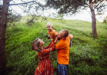 Man holds his son hugging expecting woman in the forest