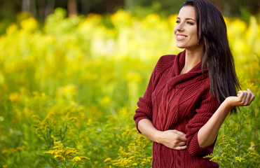 Portrait of beautiful brunette woman in autumn red sweater. Welcome warm autumn. Cute girl on a golden autumn background.