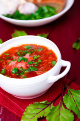 Ukrainian traditional borsch. Russian vegetarian red soup  in white bowl on red wooden background.  Borscht, borshch with beet.