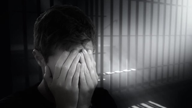 Prisoner Crying In His Cell. Lonely man crying in his cell inside a prison