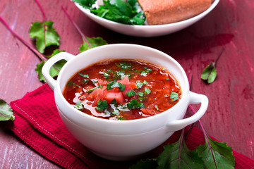 Ukrainian traditional borsch. Russian vegetarian red soup  in white bowl on red wooden background.  Borscht, borshch with beet.