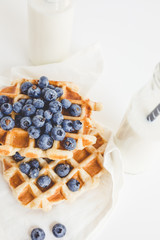 delicious breakfast of waffles with blueberries and two bottles of milk