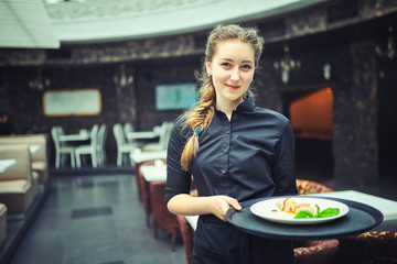 Waiters carrying plates with food, in a restaurant. - obrazy, fototapety, plakaty