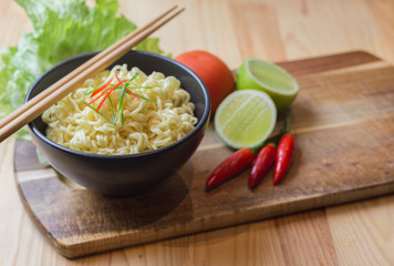 Instant noodles in white black on wood background, Asian meal on a table
