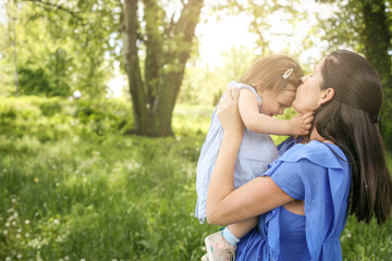 Pregnant mother playing with little daughter in park. Mother and daughter in meadow.