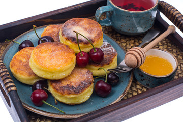 Delicious curd cheese cakes with honey and cherries on tray