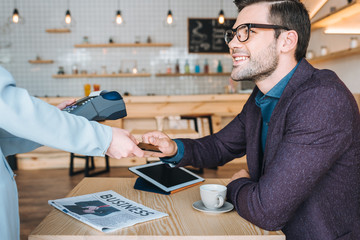 businessman paying with credit card in cafe