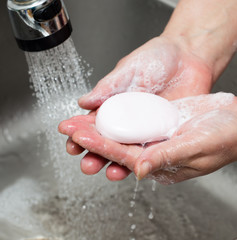Fototapeta premium Woman washes her hands with soap under a tap of water