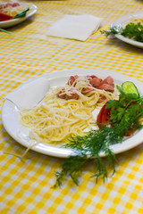 Pasta with sausage and tomatoes with greens on a white plate