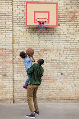 rear view of father and son playing basketball together