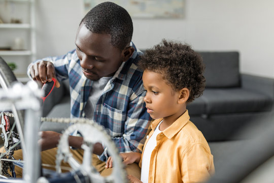 pensive african-american father and son repairing bicycle - Powered by Adobe