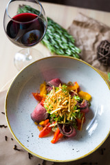 Close-up of salad with beef, cherry tomatoes, pepper, lettuce, background of a glass of red wine, rosemary, beautiful trendy serve, restaurant, dinner, lunch, delicious food, high-cuisine