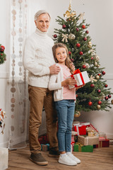 Obraz na płótnie Canvas grandfather and granddaughter with christmas gift