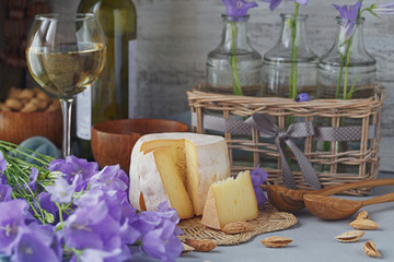 A head of fresh organic cheese served with bread, nuts, white wine and summer flowers.