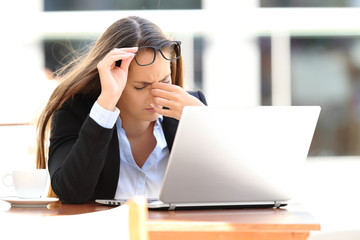 Tired worker suffering eyestrain in a coffee shop