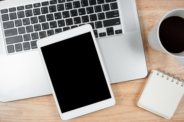 Tablet computer with blank screen on top wood table. Top view.