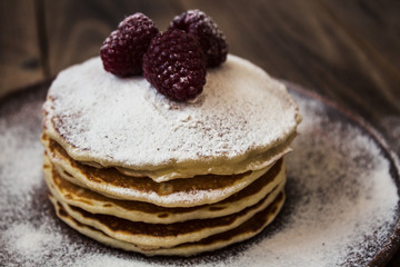 stack of pancakes with sugar powder and raspberry