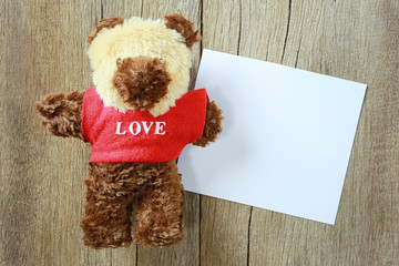 Teddy Bear is placed on old brown wood floor.