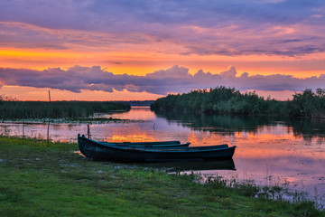 Fototapeta na wymiar Boats anchored to shore in the delta at sunset