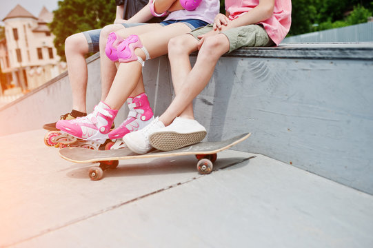Close-up photo of male legs on skateboard and female legs in rollerblades and protection.