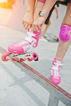 Young woman putting on rollerblades outdoor.