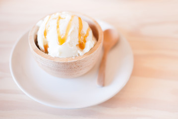 vanilla iced-cream topped with caramel sauce, served in wooden cup, selective focus