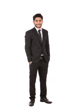Full length shot of a happy handsome young businessman with hand in pocket smiling and looking to you, guy wearing black suit and black tie, isolated on white background