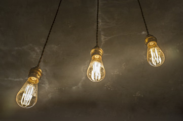 Three hanging light bulbs over oxide dark color concrete background