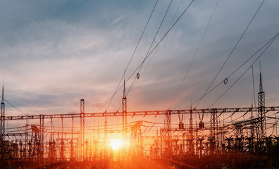 distribution electric substation with power lines and transformers, at sunset.
