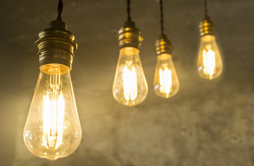 Four hanging light bulbs over oxide dark color concrete background