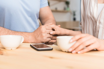 cropped shot of young couple drinking coffee and holding hands