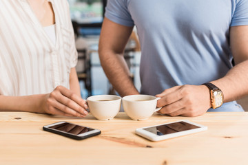 cropped view of young couple drinking coffee at bar counter