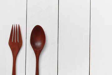 Wooden spoon and wooden fork on white wooden floor.