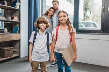 kids ready for school with parents on background