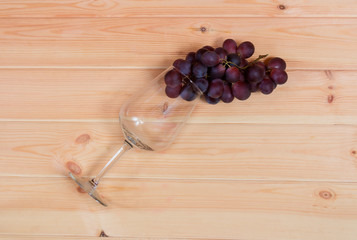 Empty wine glass with red grape on wooden background