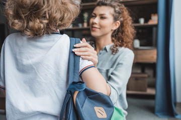 beautiful young mother preparing her little son for school