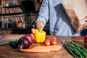 cropped shot of man unpacking vegetables at kitchen