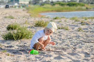 Little girl playing in the sand near the sea.