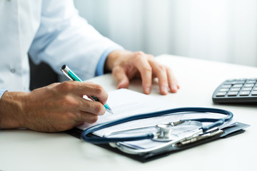 doctor writing prescription at desk in clinics office