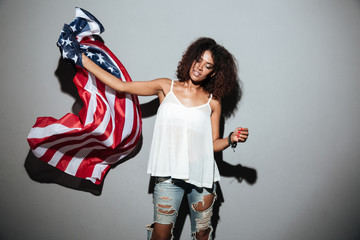 Naklejka na ściany i meble Pretty young african woman waving with USA national flag