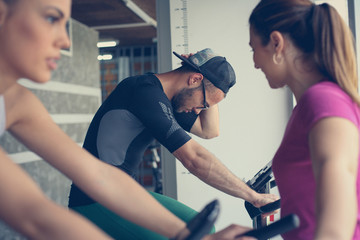 Obraz premium Two smiling young people exercise in gym. People workout in gym with personal trainer.