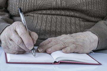 closeup wrinkled hands of a person writing