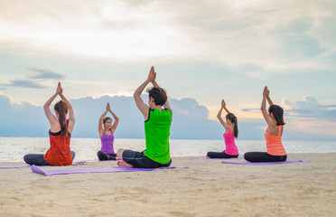 Yoga class at sea beach in evening sunset ,Group of people doing namaste poses with clam relax...