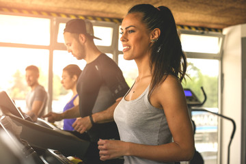 Young man and women workout in gym. Friends together in gym on the treadmill.