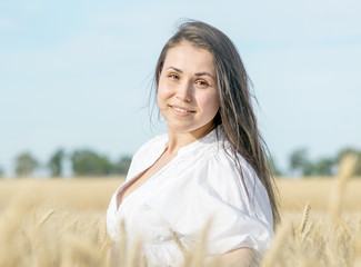 Pertrait of a pretty sexy female smiling in wheat field at warm summer day