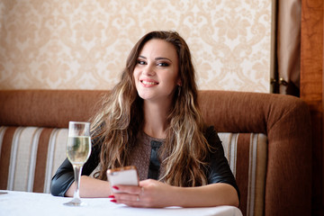 Beautiful girl with a phone at a table in the restaurant.