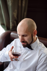 A brutal man tasting cognac.